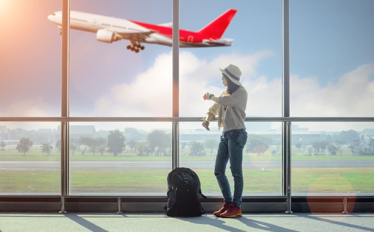 image of someone watching a plane take of through the terminal windows