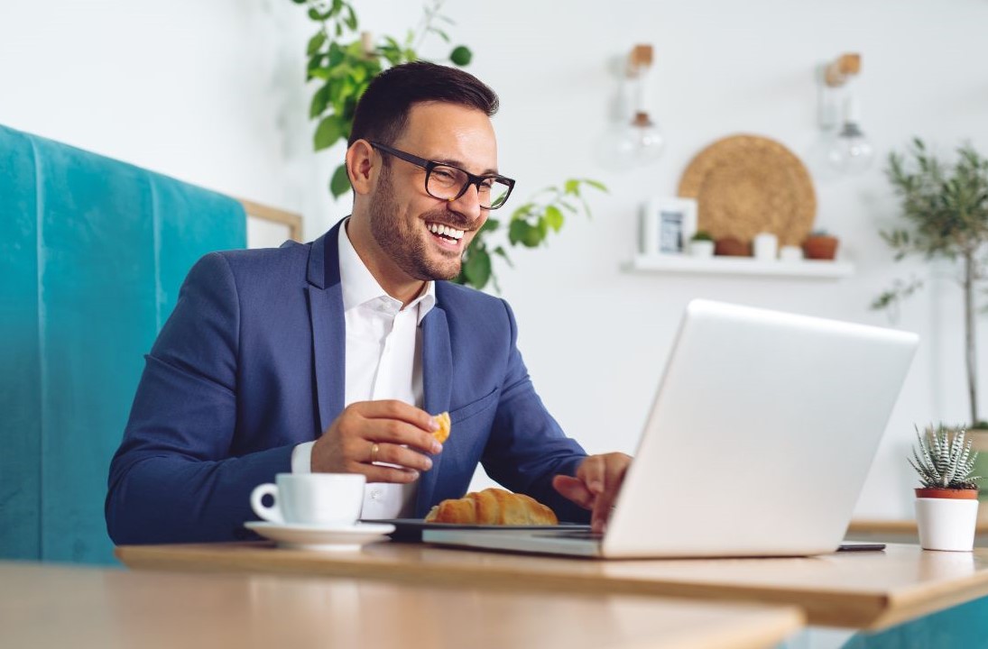 image of a man looking at his laptop open with a criossont in his hand