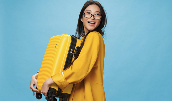 Asian woman wearing glasses holding a yellow suitcase